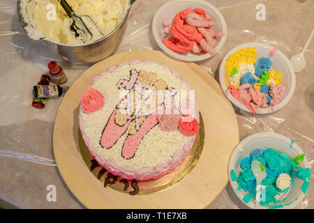 La decorazione di una torta di compleanno con zucchero a velo scarpe da ballo, Foto Stock