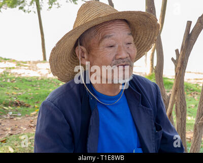 Ritratto di un locale uomo maturo di fumare in un piccolo villaggio di montagna vicino a Kumming, nella provincia dello Yunnan nel sud-ovest della Cina nel mese di settembre Foto Stock