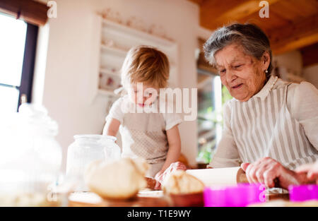 Nonna senior con piccole toddler boy fare torte a casa. Foto Stock