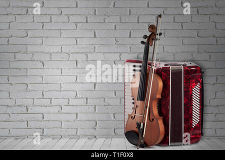 Vintage red fisarmonica e violino sul muro di mattoni in background Foto Stock