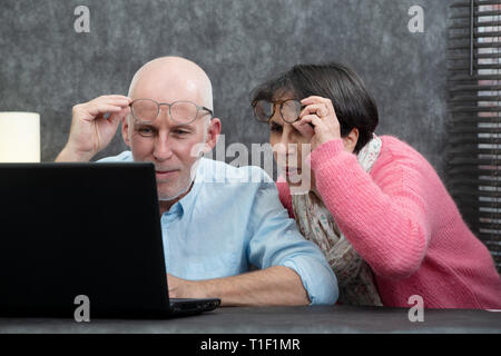Una coppia senior utilizzando laptop, essi avendo difficoltà e problemi di visione Foto Stock