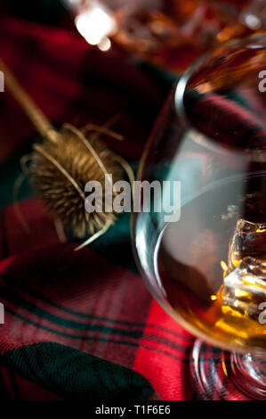 Bicchiere di whisly scozzese su una tabella con i tradizionali tartan e un thisly, simbolo della Scozia Foto Stock