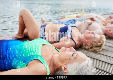 Gruppo di anziani che giace disteso su un pontile sul lago in estate in vacanza Foto Stock