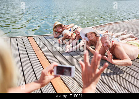 Persona che prende una foto con lo smartphone dal senior presso il lago in vacanza estiva Foto Stock