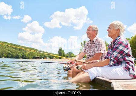 Felice coppia senior si rilassa mentre la pesca insieme dal lago in estate Foto Stock