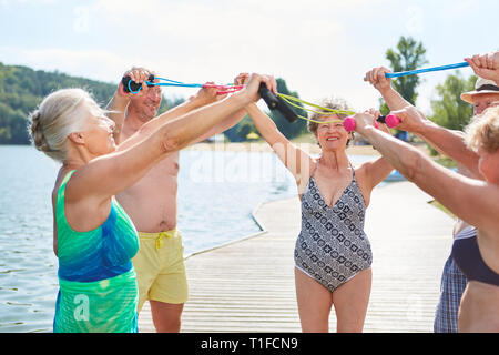 Gli anziani fare ginnastica con corda da salto in un gruppo riabilitativo presso il lago in estate Foto Stock