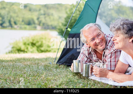 Coppia senior nella tenda di bere una tazza di caffè mentre all'aperto su vacanze estive Foto Stock