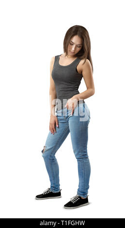 Giovane donna in top senza maniche e jeans in piedi in mezzo giro a guardare verso il basso isolati su sfondo bianco. Foto Stock