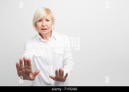 Vecchio e preoccupato della donna si mostra che essa è piuttosto categorico. Lei è il rifiuto. Vista di taglio. Isolato su sfondo bianco Foto Stock
