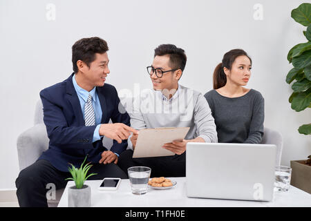 Non è colpa mia! Orinato giovane uomo che parla di psichiatra e gesticolando mentre sua moglie seduta vicino a lui e mantenendo le braccia incrociate Foto Stock