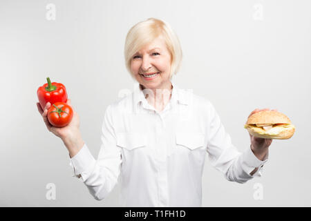 Una foto del dilemma che questa signora ha. Vi è una buona e sana pasto su un lato e una gustosa ma non sano hamburger sull'altro lato. Isolato Foto Stock