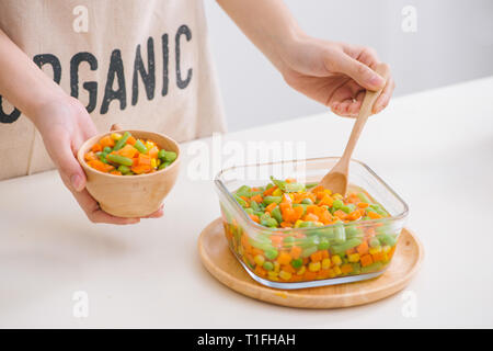 Siviera di vapore fresco raccolte verdure giovani compresi crinkle tagliare le carote affettate, piselli e patate per un sano accompagnamento a cena Foto Stock