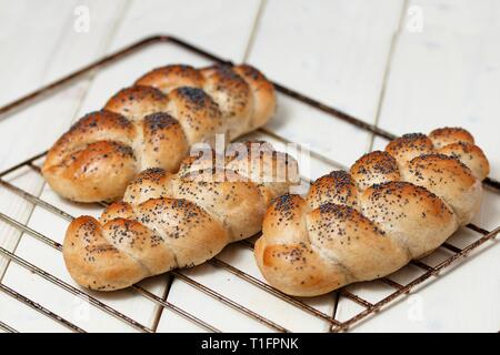 Freschi di forno in casa salato senza glutine panini cosparso con semi di papavero sulla griglia in metallo bianco su una superficie di legno Foto Stock