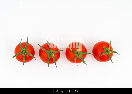 Alcuni piccoli pomodori su una superficie bianca Foto Stock