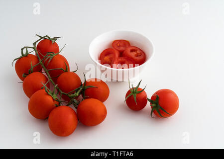 Alcuni piccoli pomodori su una superficie bianca Foto Stock