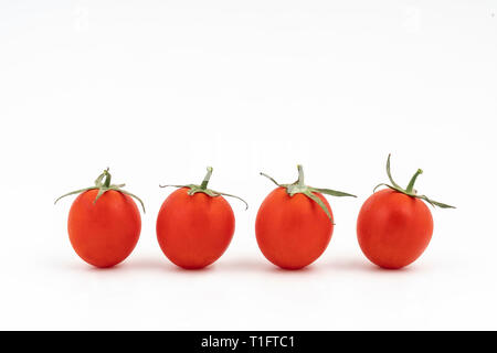 Alcuni piccoli pomodori su una superficie bianca Foto Stock