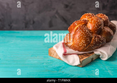 Challa pane , tradizionale pane ebraico , sul piatto di legno e sfondo blu con spazio di copia Foto Stock