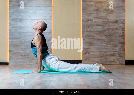L'uomo le pratiche yoga sul tappeto blu . Foto Stock