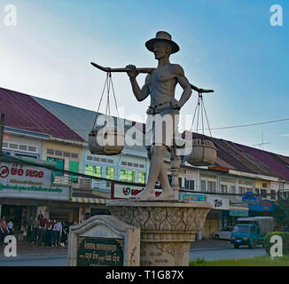 Il Peddler statua è di un uomo con un giogo sulle sue spalle, portando cesti di frutta in vendita rappresentative del commercio nella città di Battambang. Foto Stock