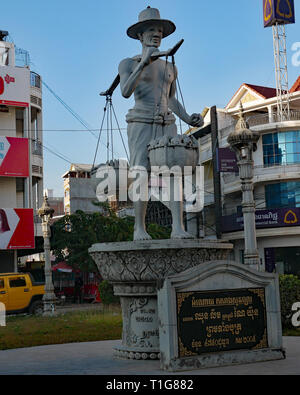 Il Peddler statua è di un uomo con un giogo sulle sue spalle, portando cesti di frutta in vendita rappresentative del commercio nella città di Battambang. Foto Stock