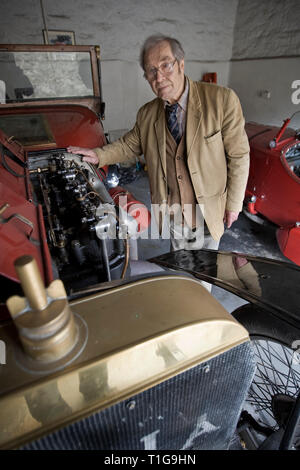 Master horologist George Daniels, raffigurato con alcuni della sua collezione di auto d'epoca nella motivazione della sua casa a Ramsey, Isola di Man. Sig. Daniels è stato rendendo orologi per oltre 60 anni ed è famoso per la creazione del co-axial escapement. Egli è uno dei pochi orologiai vivente che può creare una completa guarda a mano; compreso il caso e comporre e lui è un ex comandante della Clockmakers' Company of London. Foto Stock