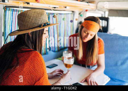 Due giovani donne utilizzando smart mobile e tostare nel loro camper Foto Stock