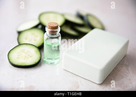 Estratto di cetriolo in piccola bottiglia con barra di sapone e fette di cetriolo. Foto Stock