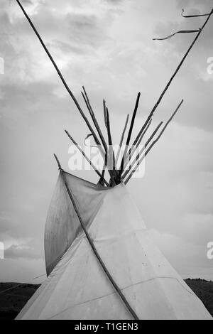 Una stretta fino al tramonto della metà superiore di una tende Tepee con drammatica sky in pianure occidentali in bianco e nero Foto Stock