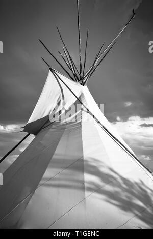 Una vista ritagliata di un tende Tepee con drammatica sky in pianure occidentali al tramonto in USA in bianco e nero Foto Stock