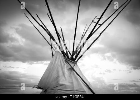 Un tagliato vicino fino in bianco e nero vista della sommità di un tende Tepee con drammatica sky in pianure occidentali al tramonto negli Stati Uniti Foto Stock