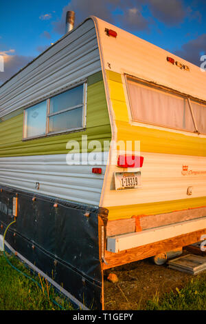 Un vecchio camper trailer sembra aver visto giorni migliori ed è ora disattivato la griglia vivere al tramonto nel Montana, USA Foto Stock