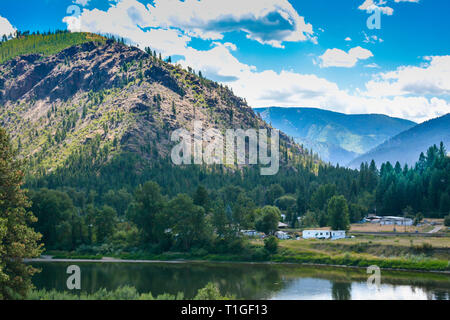 Vista delle montagne e del fiume a fianco di case e di rimorchi in remote Western Montana, USA Foto Stock