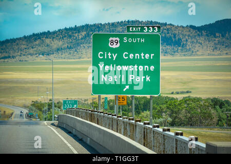 Un verde Montana interstate uscita segno per il sud 89 verso il centro della città e il Parco Nazionale di Yellowstone, con sfondo montano sulla I-90 freeway Foto Stock