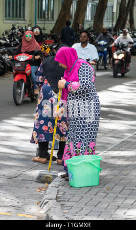 Maschio, Maldive - Febbraio 11th, 2019: una donna musulmana che indossa il hijab spazzamento e pulizia della strada nel maschio, Maldive. Foto Stock