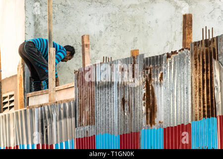 Maschio, Maldive - Febbraio 11th, 2019: UN MASCHIO lavoratore edile su un tetto senza casco nel maschio, Maldive Foto Stock