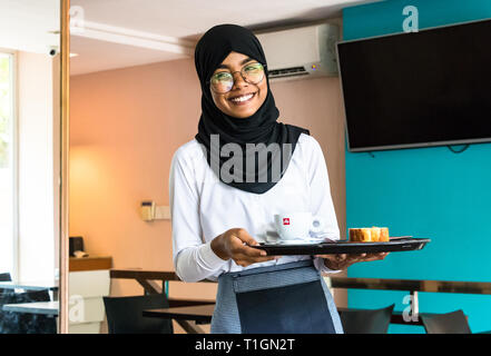 Maschio, Maldive - Febbraio 11th, 2019: Ritratto di una donna musulmana che indossa il hijab e occhiali che lavora come cameriera in un negozio di caffè nel maschio, Maldive Foto Stock