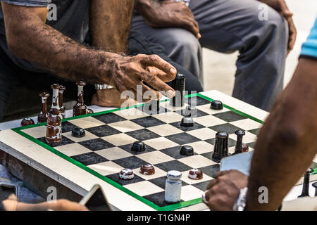 Un uomo pronto a spostare un pezzo di un gioco di scacchi posti esterni nel maschio, Maldive. Foto Stock