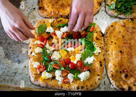 Mani dell'uomo facendo preparare un colorato stile romano pizza italiana in una pizzeria/trattoria Foto Stock