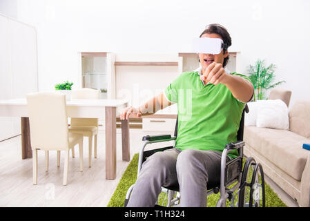 Giovane uomo bello in carrozzella a casa Foto Stock
