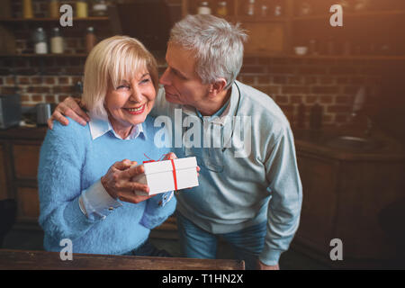 Bella senior mn e donna sono in piedi in cucina. Ella ha Foto Stock
