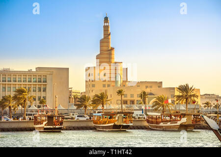 Tradizionale dhow di legno ancorata al porto Dhow nella baia di Doha con spirale Moschea e minareto in background al tramonto. Vista dal lungomare Corniche Foto Stock