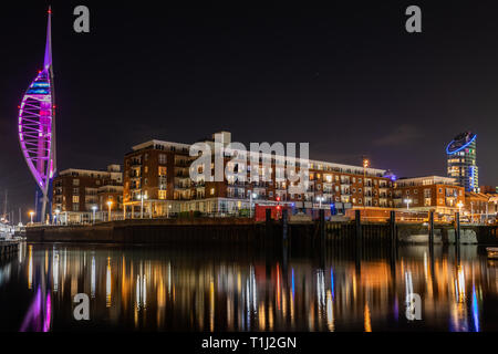 Spinnaker Tower al Gunwharf Quays Portsmouth illuminato di viola di notte per epilessia nazionale giorno riflettendo sull'acqua Foto Stock
