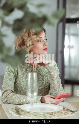 Ragazza texting il suo uomo durante l'attesa per la cena con lui Foto Stock