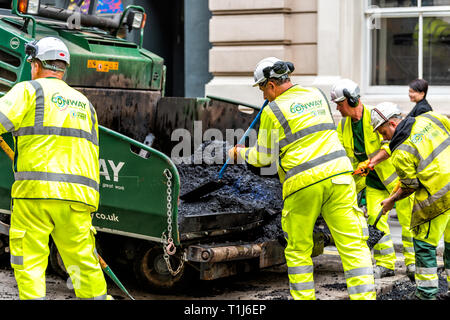 London, Regno Unito - 12 Settembre 2018: lavoratori edili con neon uniformi i giubbotti abbigliamento caldo umido nero catrame e asfalto Bitume nel sito della città Foto Stock