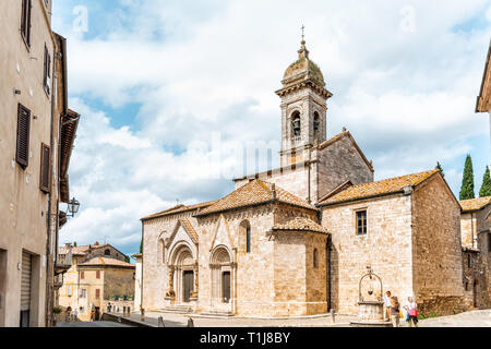 San Quirico d'Orcia, Italia - 26 agosto 2018: piccola e antica città medievale Borgo in Toscana e la famosa chiesa di torre campanaria tra alley con persone o Foto Stock