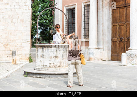 San Quirico d'Orcia, Italia - 26 agosto 2018: piccola e antica città medievale piazza del villaggio in Toscana dalla famosa chiesa con persone turisti tenendo pict Foto Stock