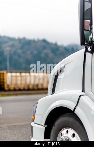 La parte anteriore di professionale di grado industriale la cabina e il cofano della moderna big rig pulito bianco semi carrello con ruota anteriore parcheggiato sul parcheggio vicino alla wareh Foto Stock