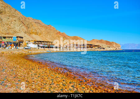 DAHAB, Egitto - 16 dicembre 2017: la costa del Buco Blu località turistica con la linea di ombrosi caffetterie, ristoranti e sale lungo la riva, sul Decemb Foto Stock