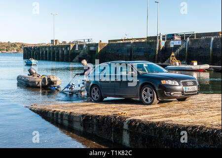 Schull, West Cork, Irlanda. Il 27 marzo, 2019. Un uomo lancia la sua costola off Schull Harbour scivolo alla fine di una bella giornata in West Cork. Il resto della giornata sarà soleggiato con alti di 12° Celsius. Credito: Andy Gibson/Alamy Live News. Foto Stock