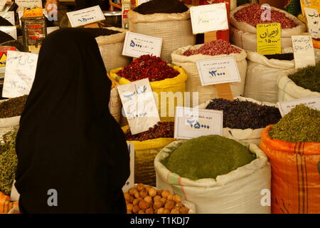 Una donna in chador in un negozio di erbe in un mercato persiano. Foto Stock